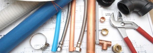 Copper pipes, fittings and tools laid out on plans
